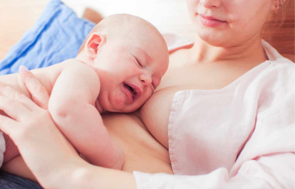 A baby with torticollis cries while breastfeeding