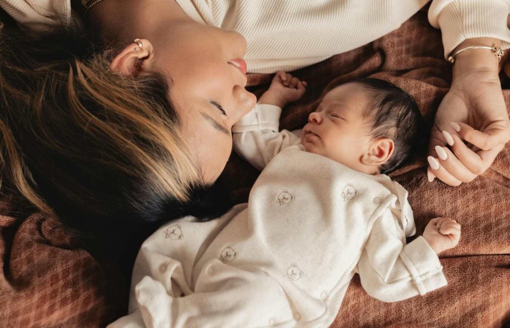 A happy and relaxed baby sleeps next to his mama